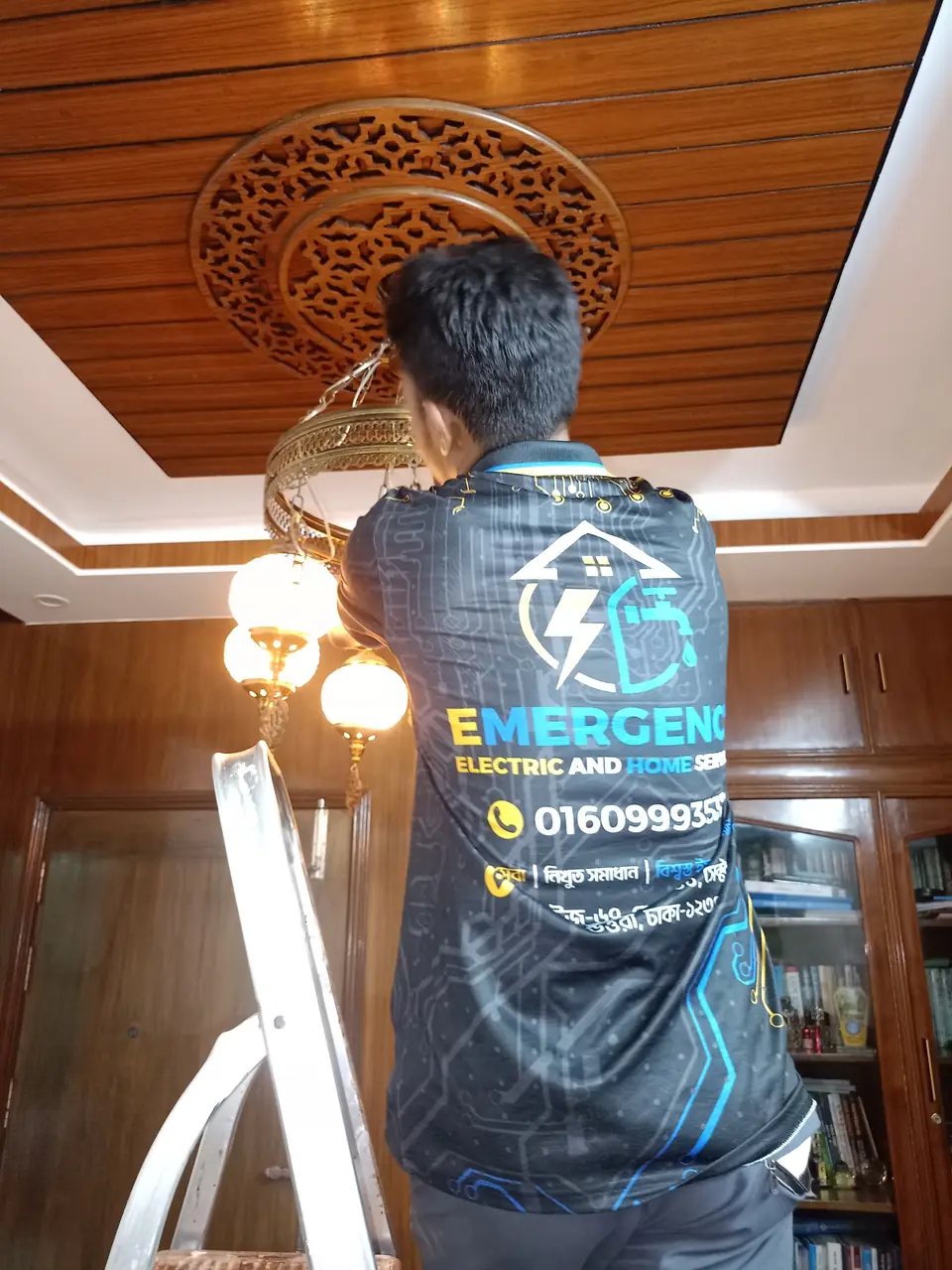 Electrician installing a chandelier on a wooden ceiling