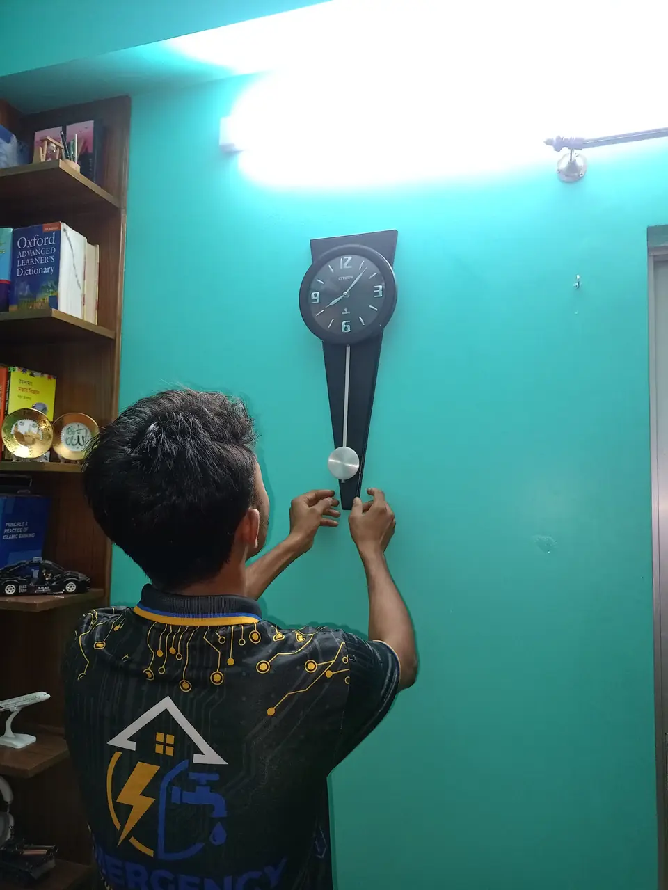 Technician fixing a wall clock on a painted wall